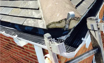 Close-up of mesh gutter guard fitted along a tiled roof edge