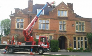 Elevated access platform reaching the roof of a large period building for high-level roof cleaning in Dover